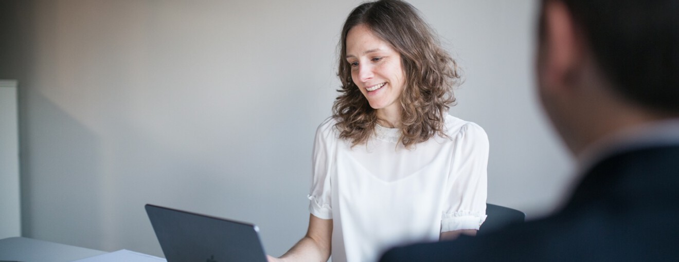 Junge Frau und junger Mann hinter Laptops lächelnd