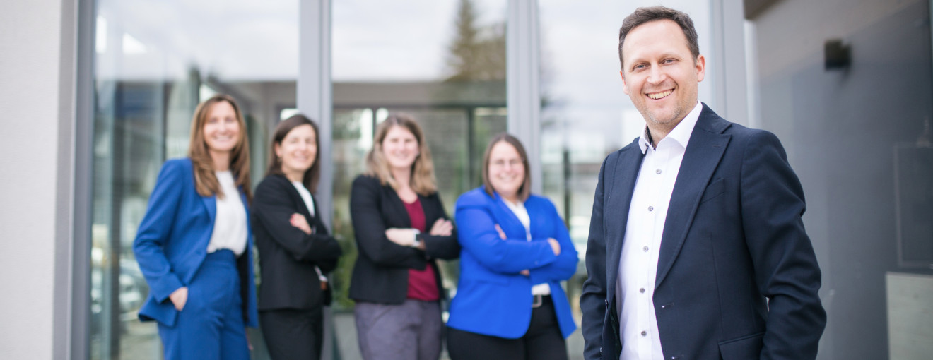 Gruppenfoto von Mitarbeiter im Vordergrund und Kolleginnen im Hintergrund