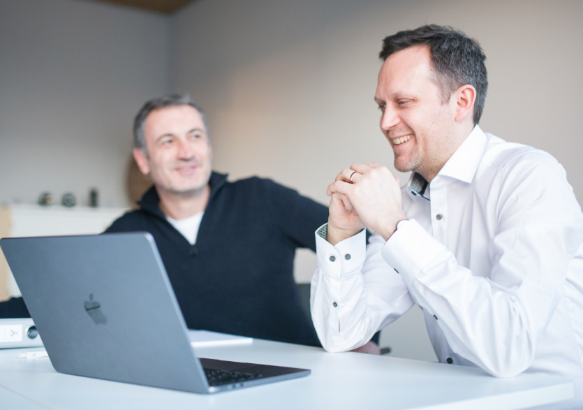Zwei Mitarbeiter vor dem Laptop unterhalten sich